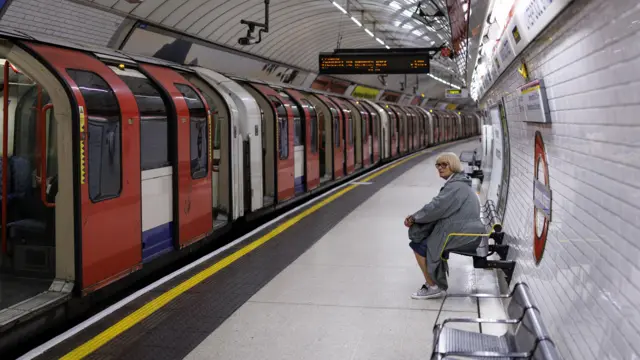 A woman sits on a bench in an empty Tube station