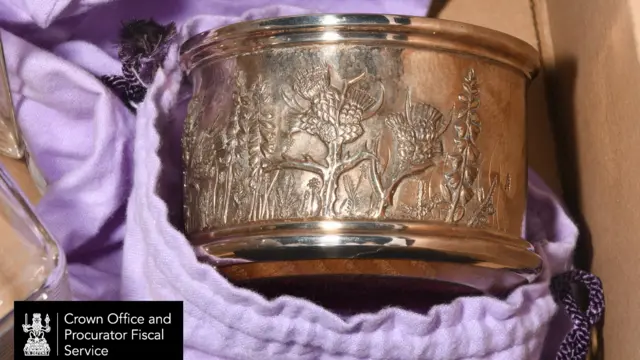 A bronze coloured object with flowers imprinted on it.