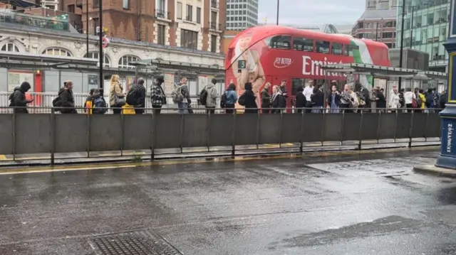 People queuing up at a bus stop outside Victoria station