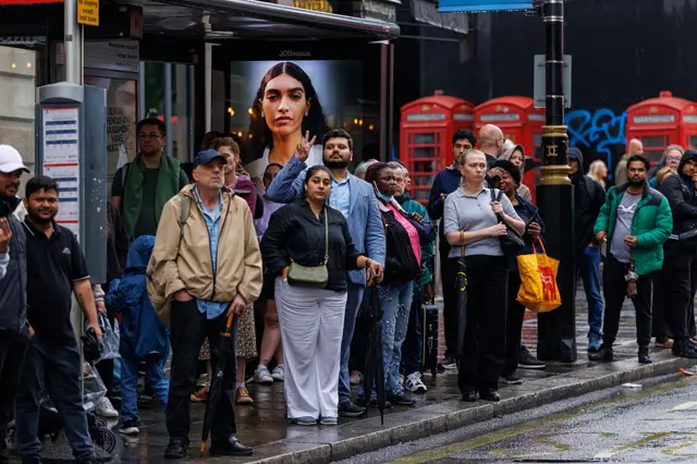 Line of commuters wait for bus outside Charing Cross station