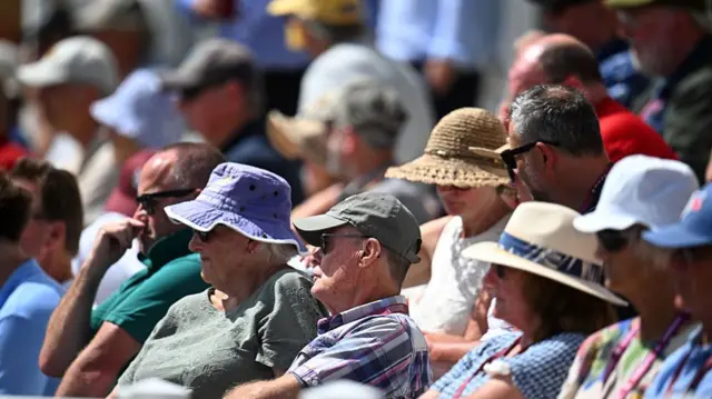 Spectators wearing hats watching Somerset at Taunton in the hot sunshine