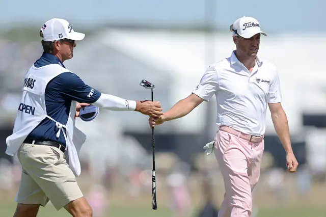 Justin Thomas hands a club to his caddie