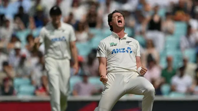 Matt Henry, wearing whites, clenches his fists and throws his head back, roaring
