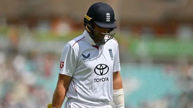 Joe Root, wearing a white shirt and blue helmet, walks off with his head bowed