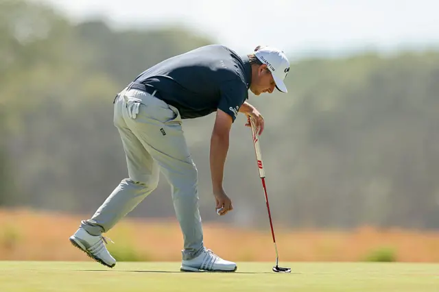 Emiliano Grillo bends down