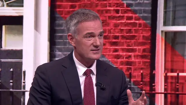Business Secretary Peter Kyle sits wearing a dark suit and a red tie. There is a graphic of Number 10 Downing Street behind him