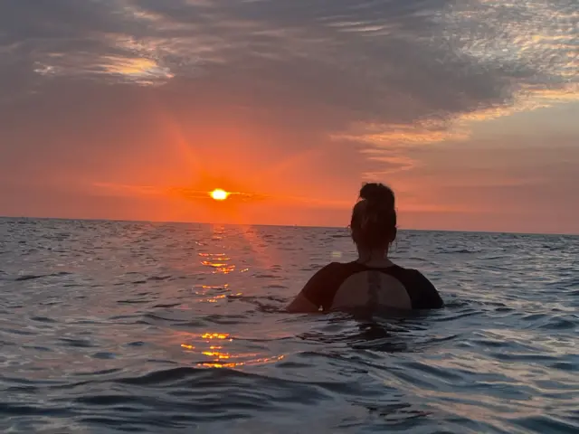 Swimmert in the sea with the Sun behind them