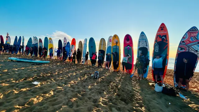 Surfers stand up their boards to recreate Stonehenge at the beach.
