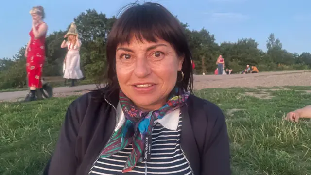 A woman in a jacket is sitting on some grass.