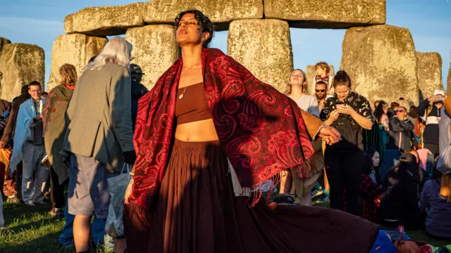 A woman wearing red in the sun at Stonehenge