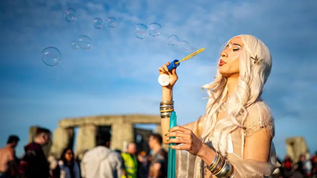A woman blows bubbles at Stonehenge