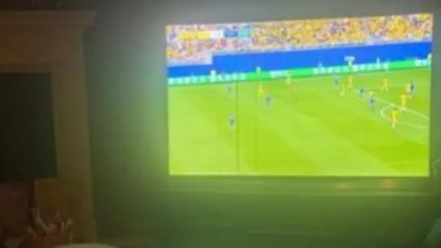 A picture of someone watching the game on a TV