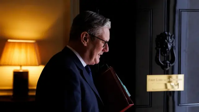 Keir Starmer steps out of the door at 10 Downing Street holding several folders