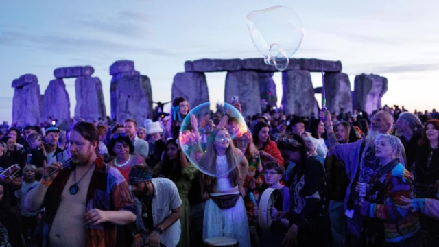 A crowd in front of Stonehenge. There's big bubbles in the air.
