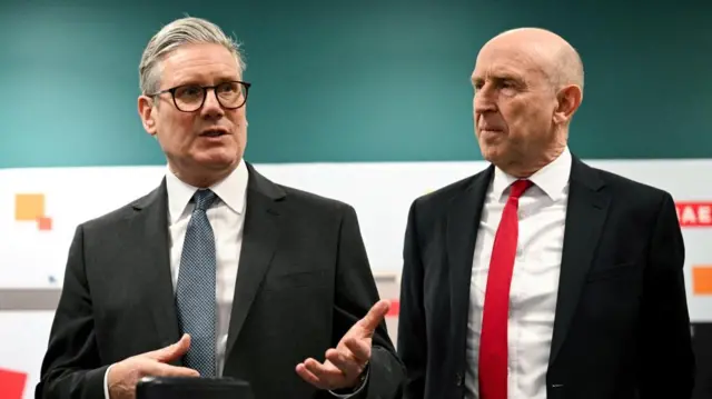 Keir Starmer stands next to John Healey during a joint visit in Barrow-in-Furness on March 20 2025