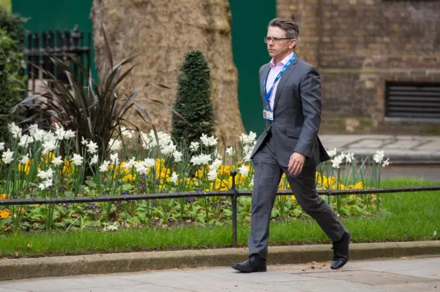 James Lyons, who has grey hair and glasses and is wearing a suit and shirt, walks into No 10 in 2020