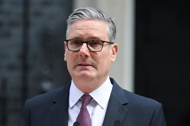 A visibly emotional Keir Starmer, who is wearing a suit and tie, stands in front of a lecturn outside 10 Downing St