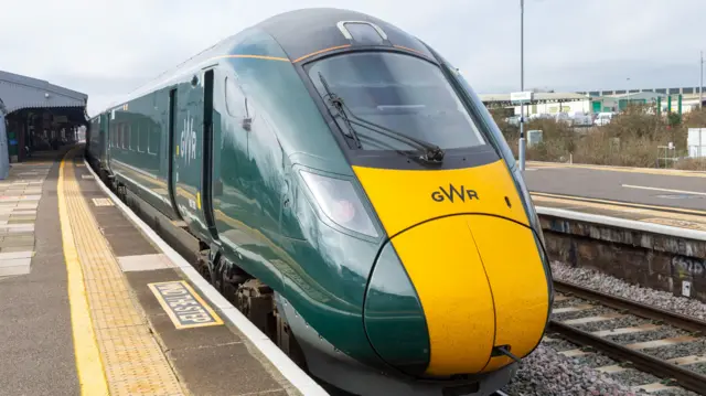 A train bearing the GWR logo is pictured stopped at a station.