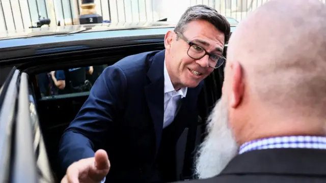 Burnham greeting someone as he steps out of a car