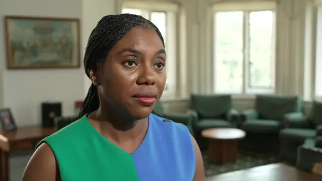 Kemi Badenoch speaks in an interview. She is wearing a green and blue top