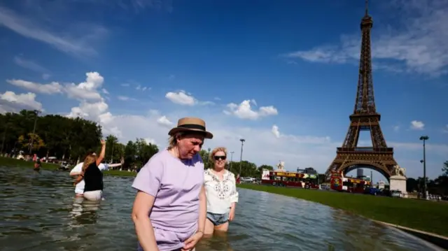 Several people try to cool off in a fountain in front of the Eiffel Tower in Paris. They have removed their trousers to go into the fountain