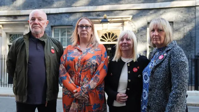 Steve Kelly, Charlotte Hennessy, Margaret Aspinall and Sue Roberts stand in front of the black door of 10 Downing Street