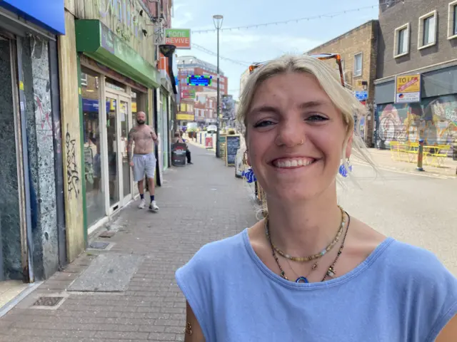 A woman with blonde hair and a blue top smiles at the camera.