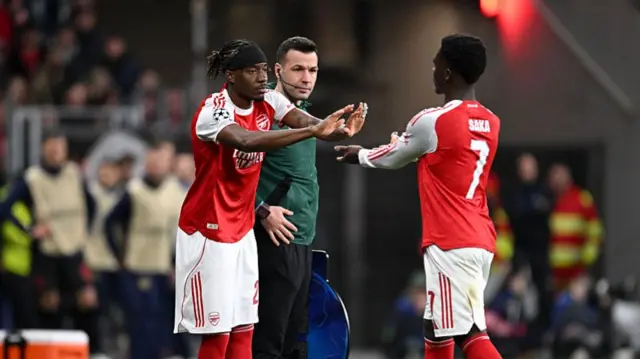 Noni Madueke of Arsenal reacts with Bukayo Saka as he enters the pitch as a substitute during the UEFA Champions League 2025/26 Round of 16 First Leg match between Bayer 04 Leverkusen and Arsenal FC at BayArena on March 11, 2026 in Leverkusen, Germany.