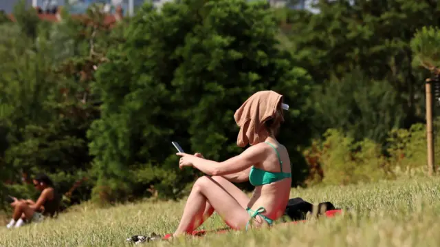 A woman covers her face in a London park