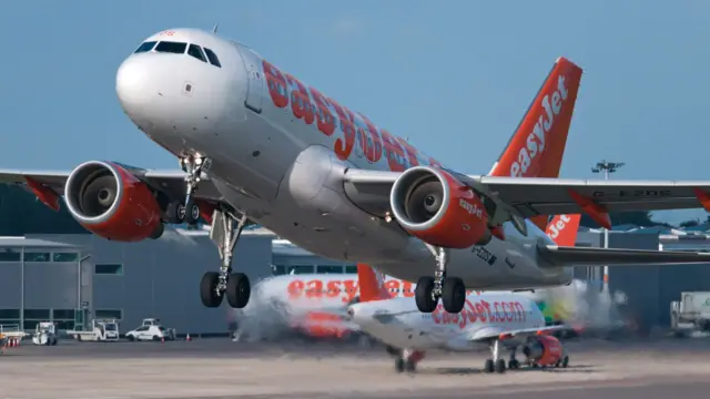 A white and orange EasyJet branded plane taking off from Bristol Airport.