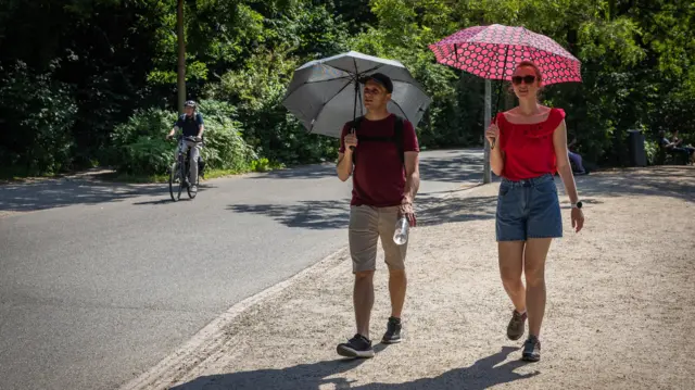People shelter from the sun under umbrellas in Vondelpark in Amsterdam, the Netherlands, 19 June 2026. Due to the warm weather, the National Heat Plan is in effect nationwide.