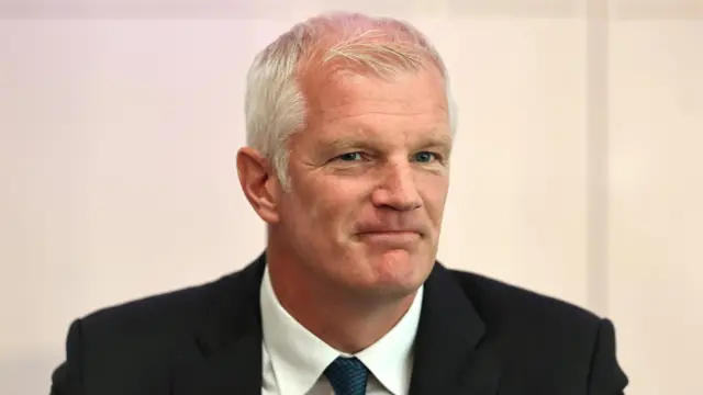 Al Carns, a man, wearing a suit, white shirt and dark blue tie.