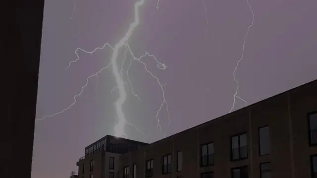 A large lightening strike above a block of flats at night.