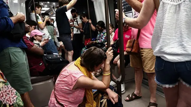 A woman sits on the floor of a crowded carriage on metro line 11 during a heatwave in Paris, Ile-de-France, France, June 22, 202