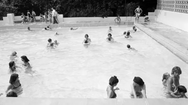 A black and white photo of people in an outdoor swimming pool