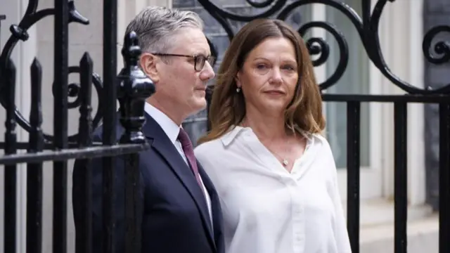 Keir Starmer and Victoria Starmer stand outside the door to No 10 Downing Street.
