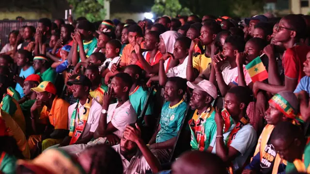 Senegalese football fans gather in front of a giant public broadcast screen at the Place de la Nation square in the capital city of Dakar, Senegal, on June 23, 2026, to watch the Senegal national team compete against Norway in the 2026 FIFA World Cup.
