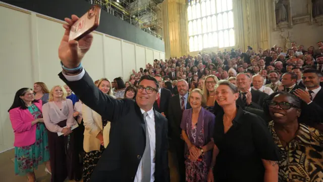 Andy Burnham holds up phone for selfies with MPs
