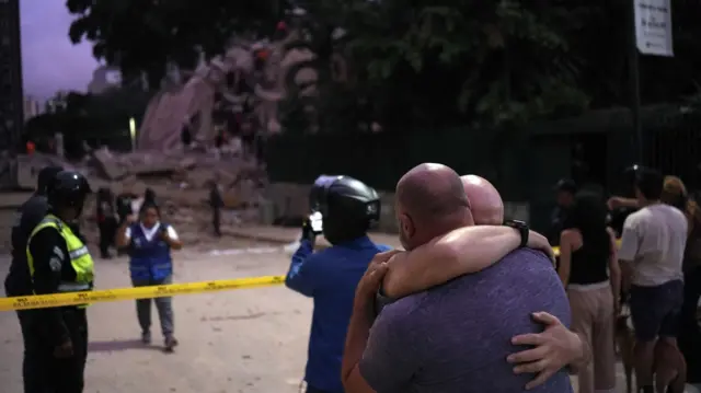 Two men hug after the quake in front of a collapsed building.