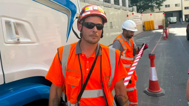 A construction worker in a high visibility jacket, hard hat and sunglasses pictured in London