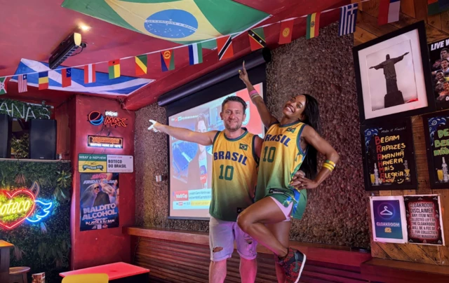 a man and woman wearing Brasil vests in a bar