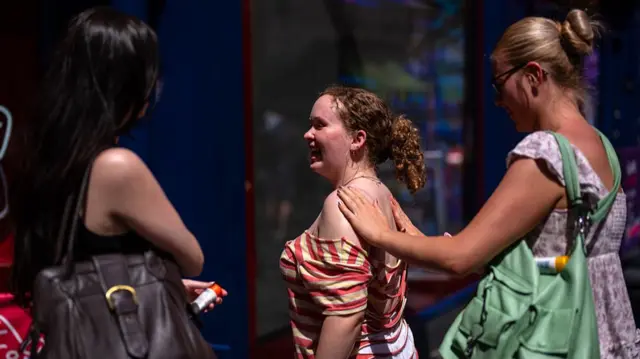 Woman rubs sunscreen on friends back in the heatwave