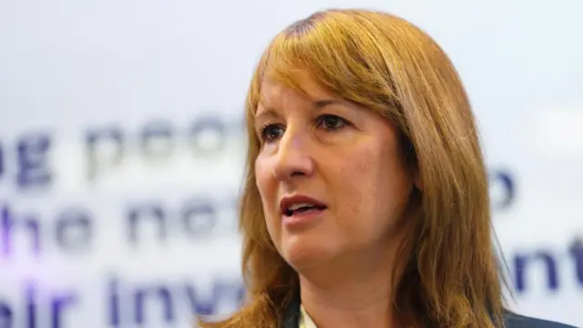 Rachel Reeves has shoulder length reddish brown hair, and wears a white shirt and blue jacket