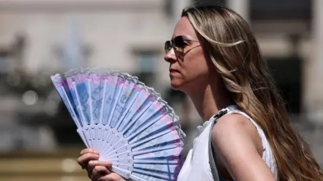 A woman uses a fan to cool down in London during June heatwave
