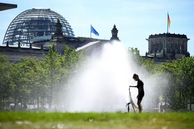 A woman cools down outside the Reichstag in Berlin earlier today