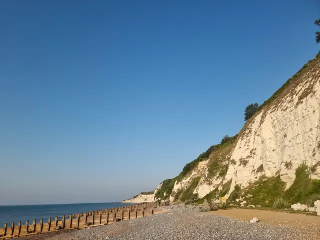 White cliffs look over beach, with clear skies up above