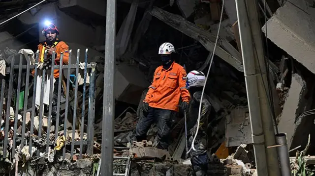 Rescuers search through rubble of a collapsed building
