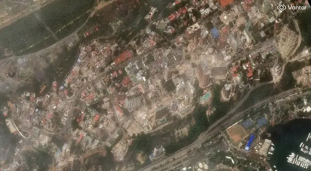 Vantor satellite image shows extensive earthquake damage including collapsed high-rise apartment buildings and heavily damaged structures in the Playa Grande neighborhood of La Guaira.