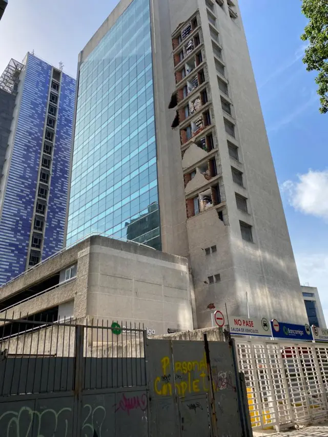 A tall damaged apartment building with walls crumbling