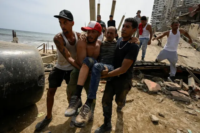 People carry an injured man, in the aftermath of earthquakes in La Guaira, Venezuela, June 25, 2026